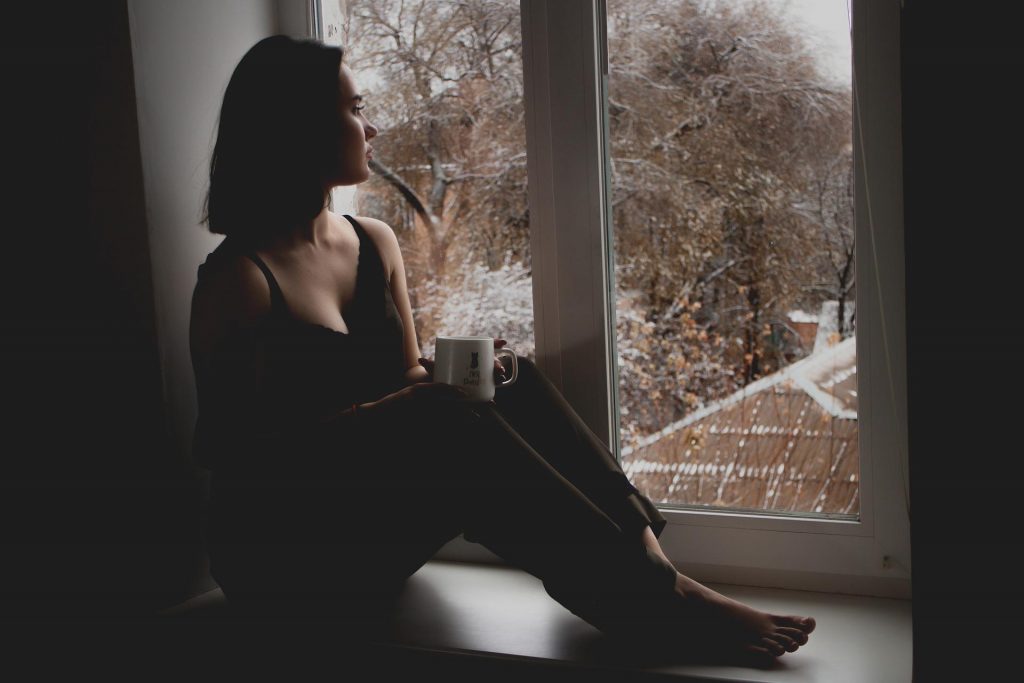 Młoda smutna dziewczyna z dystymią patrząca w okno
